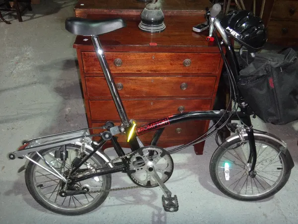 A black painted Brompton folding bike with matching pannier 'D' lock helmet and pump.