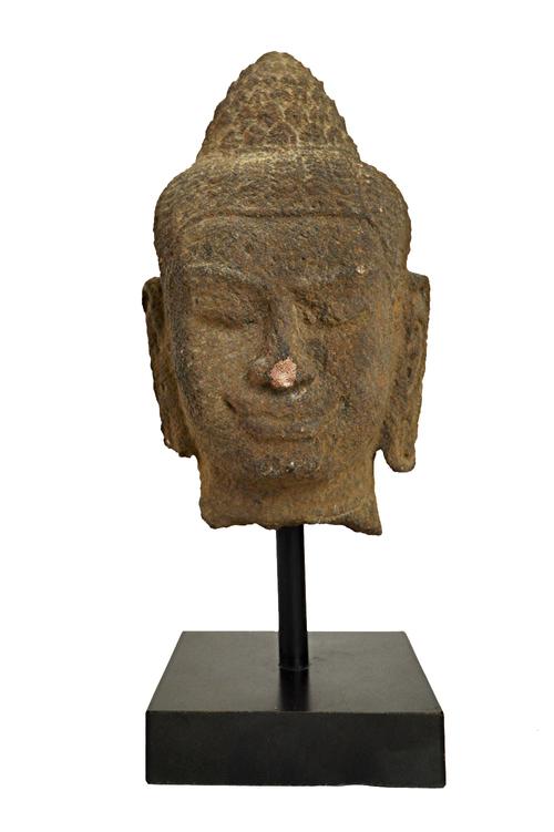 An Indonesian stone head of Buddha Shakyamuni, possibly 9th century, his face with downcast expression, elongated earlobes and curled hairdress and un