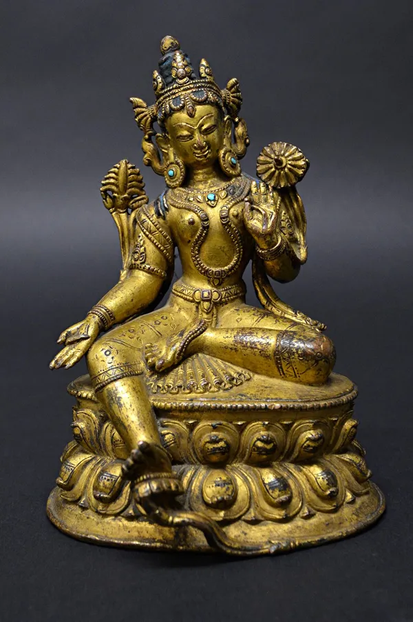 A good Tibetan gilt-bronze figure of Green Tara, 16th century, the female Bodhisattva seated in lalitasana with right foot resting on a lotus flower i