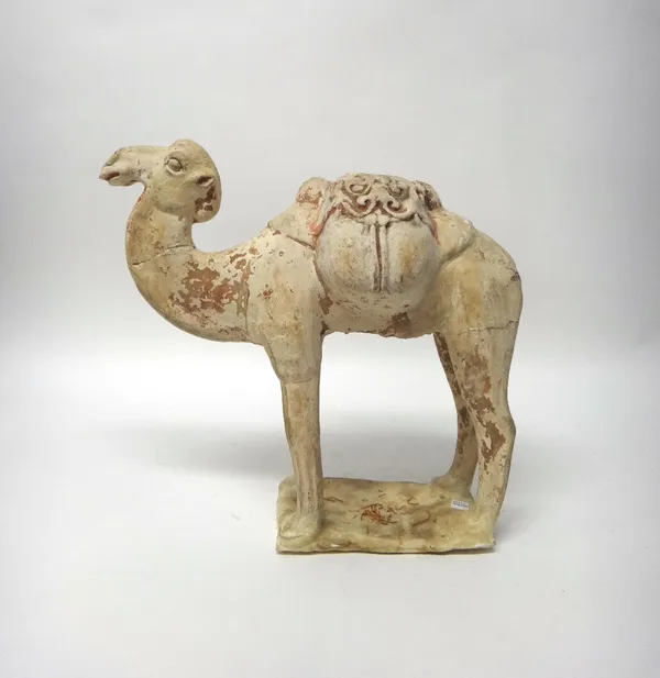 A Tang style pottery bactrian camel, standing foursquare with saddle bags across its back, covered in a white slip with traces of red pigment, (a.f),