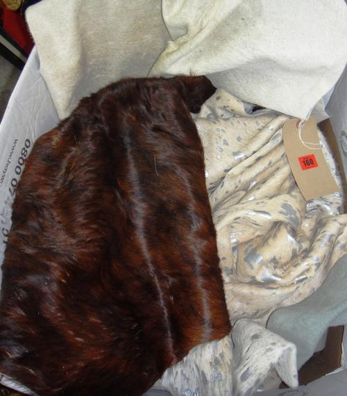 A group of four cow skin rugs, including a silvery one, together with a black sheepskin rug, (5).