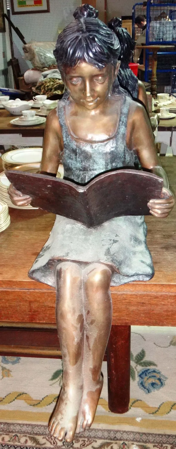 A 20th century bronze seated figure of a girl reading.