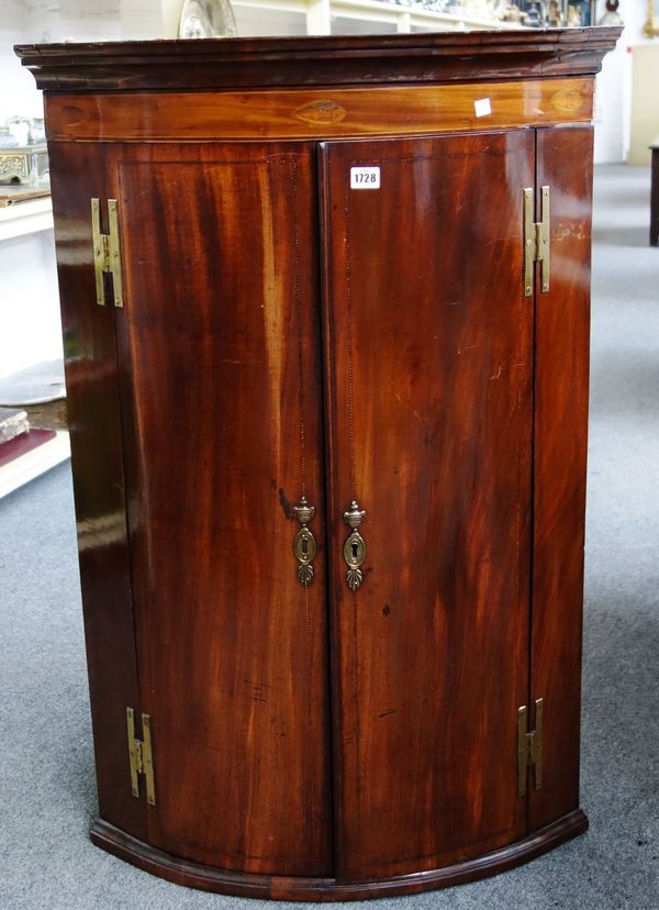 A George III inlaid mahogany bowfront two door corner cupboard, 71cm wide.