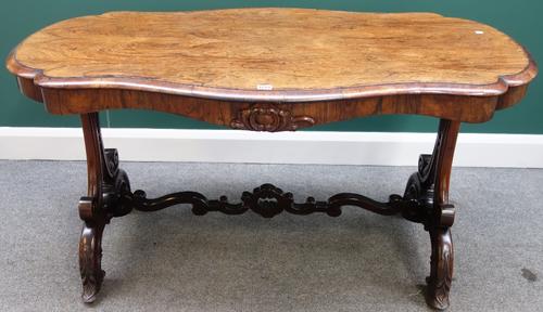 A Victorian rosewood centre table with shaped top over a carved frieze, on a pair of trestle end standards united by shaped stretcher, 136cm wide.