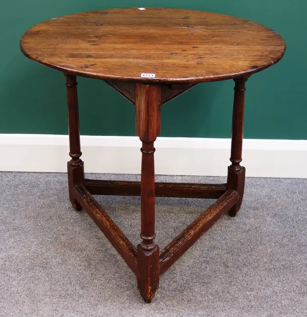 A made up 18th century oak cricket table, the oval top on three turned supports united by stretcher, 71cm wide.
