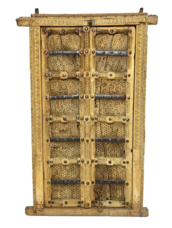 A 19th century Indian profusely carved metal bound double door and frame, 110cm wide x 166cm maximum height.  Illustrated