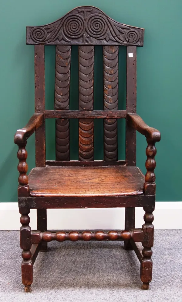 A 17th century and later oak framed open arm elbow chair, with bobbin turned supports and solid seat.