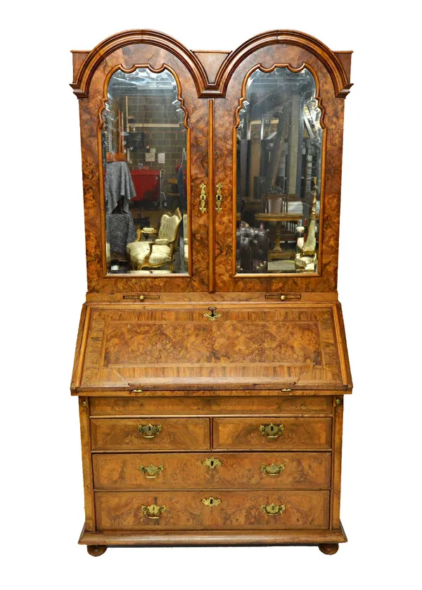 An 18th century German figured walnut double dome top bureau bookcase, the pair of mirrored doors enclosing a fitted interior, the fall also enclosing