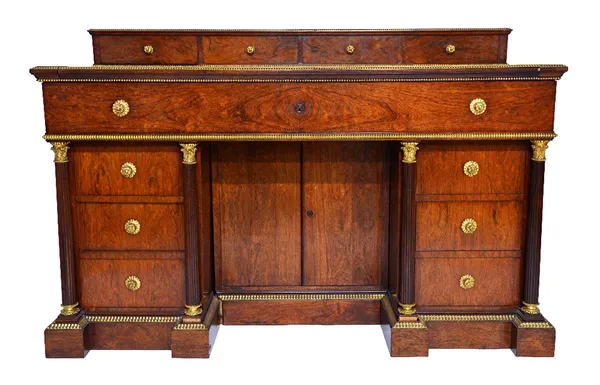 A Louis Philippe rosewood and ormolu mounted desk, with a cartonnier having four drawers above a panelled top with pull out drawer on a brass cogged w