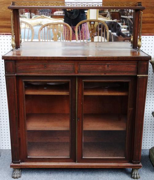 In the manner of George Oakley; a Regency brass mounted rosewood chiffonier, the mirrored ledge back over pair of frieze drawers and pair of glazed do