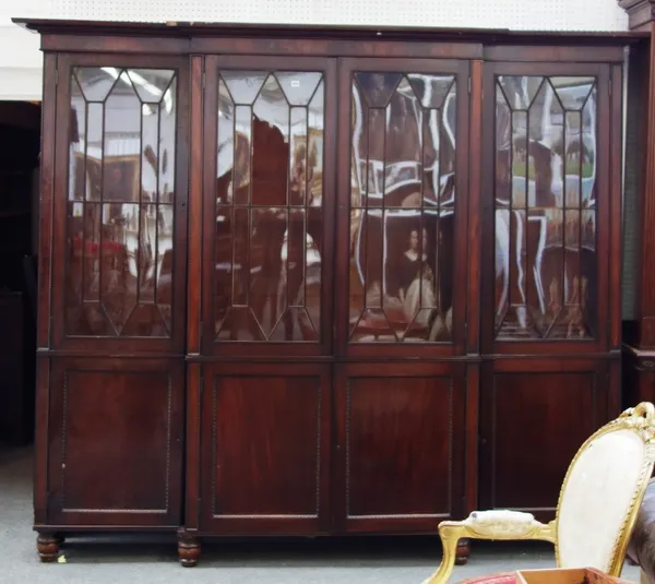 A 19th century mahogany breakfront bookcase cupboard, the four astragal glazed doors over four panelled doors, on turned feet, 265cm wide x 214cm high