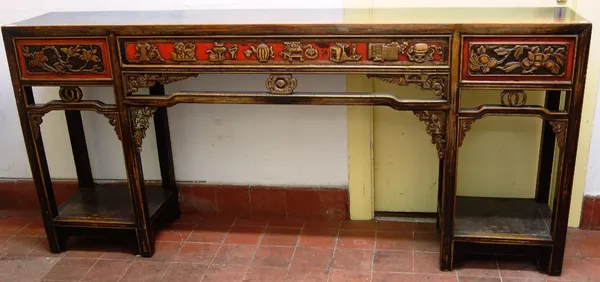 An early 20th century Chinese hardwood altar table, with pierced carved and red highlighted frieze, on eight block supports united by platform underti