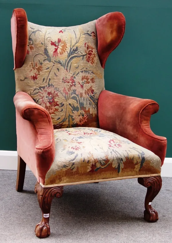 An 18th century style shaped wingback easy armchair on mahogany claw and ball supports.