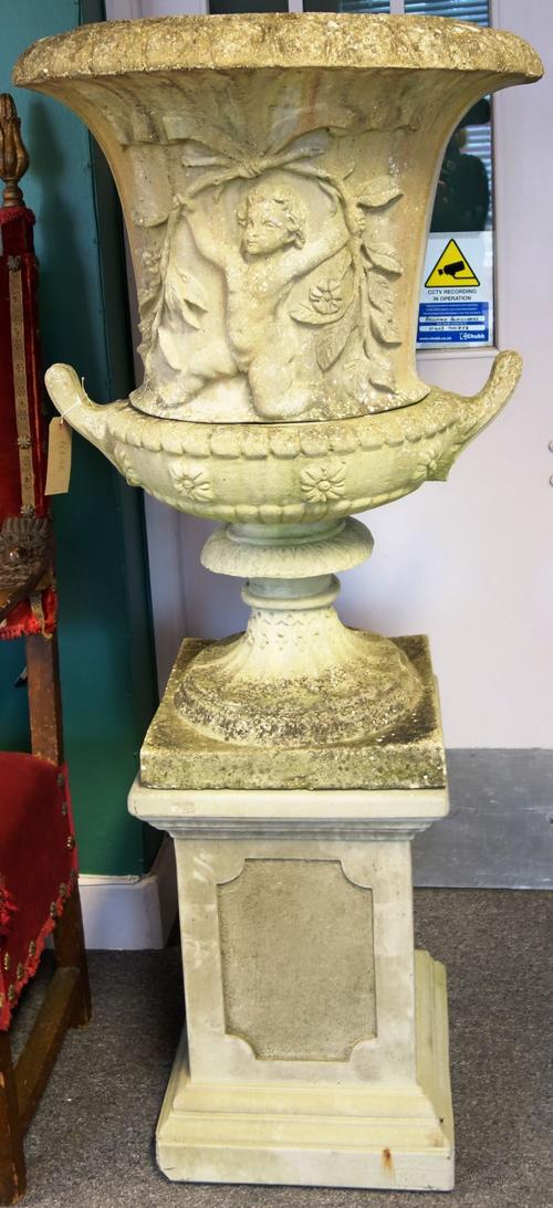A reconstituted stone jardiniere with cherub moulded body on a twin-handled turned socle and stepped square base, 160cm high.