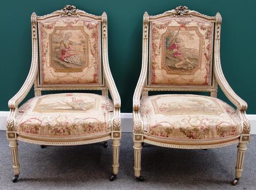 A pair of Louis XVI style cream painted easy armchairs, with bow seats on tapering fluted supports.