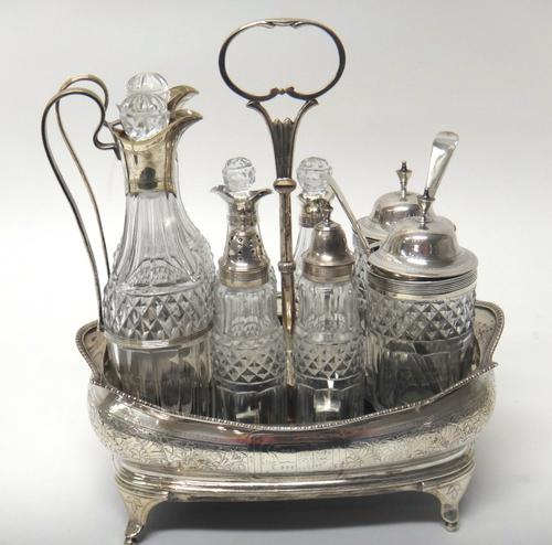 A George III silver mounted rectangular shaped cruet stand, with engraved foliate decoration and gadroon border, fitted with eight silver and plate mo