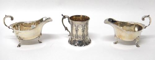A Victorian silver mug with later embossed decoration and scroll handle, London 1858, together with a pair of silver sauceboats raised on three pad fe