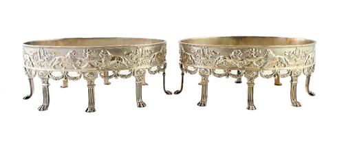 A pair of Victorian silver stands of oval form, the sides decorated with lions, fountains and scrolls, raised on eight lions paw feet, crest engraved,