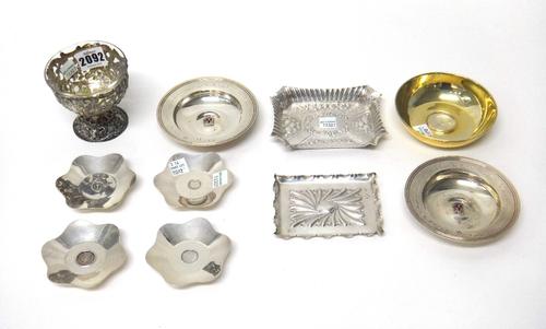 A group of silver wares, to include; a pair of Armada dishes with applied enamel badges, a set of four pin dishes inset with Maundy coins, two trinket