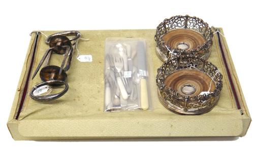 A pair of silver plated metal mounted circular bottle coasters, with scroll pierced decoration, within scroll moulded rims and having turned wooden ba