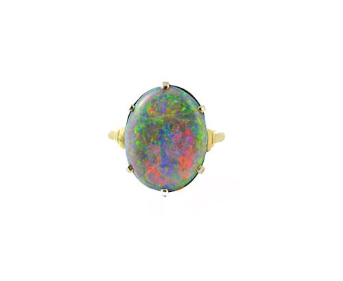 A white gold and platinum ring, claw set with an oval black opal between stepped shoulders, detailed PLAT 18 CT W.G, ring size J.  Illustrated
