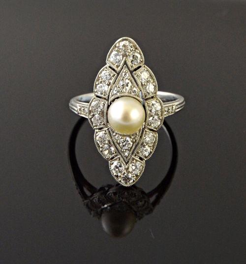 A diamond and cultured pearl ring, in a marquise shaped cluster design, mounted with the cultured pearl at the centre, in a pierced surround, mounted