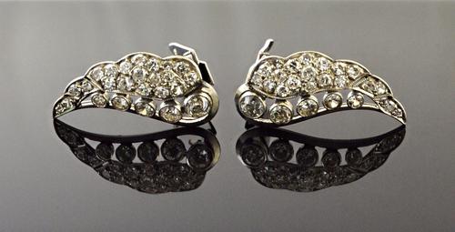 A pair of diamond set earclips, each formed as a wing, collet set with a row of five graduated circular cut diamonds and further set with smaller circ