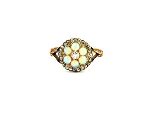 A gold, opal and diamond set cluster ring, mounted with the principal cushion shaped diamond at the centre, in a surround of six circular opals and wi