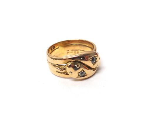 An 18ct gold and diamond set ring, designed as two entwined snakes, each head mounted with a cushion shaped diamond, ring size S and a half, London pr