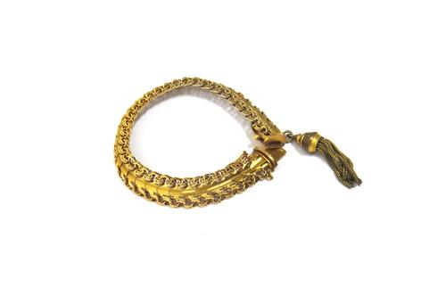 A gold bracelet, in an interwoven link design, on a snap clasp, fitted with a gold plated pendant tassel drop, estimated weight excluding tassel 21 gm