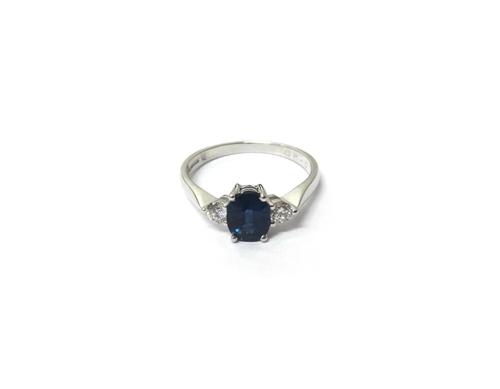 An 18ct white gold, sapphire and diamond set three stone ring, claw set with the oval cut sapphire at the centre, between two circular cut diamonds, r