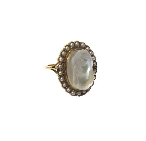 A gold, carved moonstone cameo and seed pearl set ring, mounted with the oval carved moonstone cameo at the centre, designed as the portrait of a lady