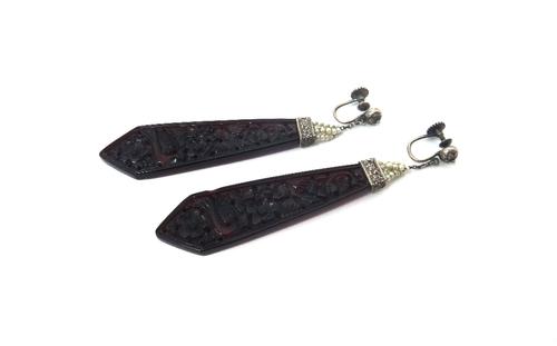 A pair of carved red amber drop shaped earrings, probably Chinese, each carved and pierced with bird and floral motifs, with seed pearl set surmounts,