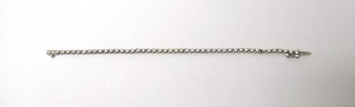 A white gold and diamond set line bracelet, claw set with a row of circular cut diamonds, on a snap clasp, with a foldover safety catch (one diamond l