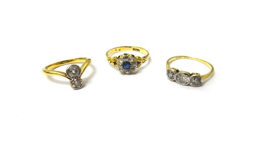A gold and diamond set two stone ring, mounted with cushion shaped diamonds, a gold and diamond set three stone ring, mounted with cushion shaped diam