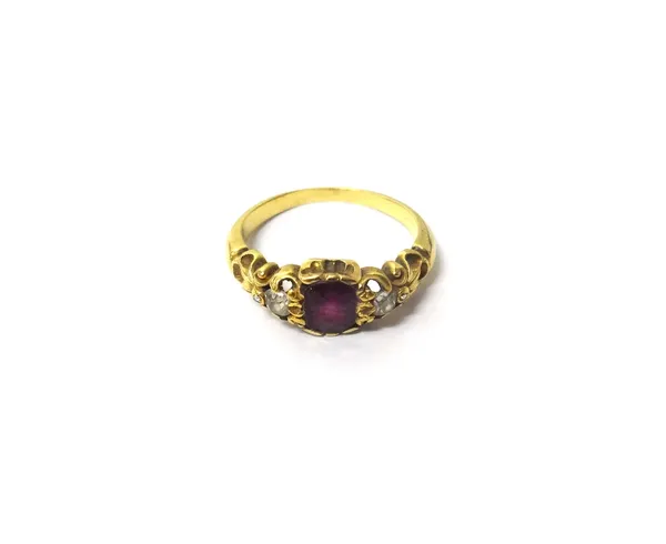 A gold, ruby and diamond set three stone ring, mounted with the cushion shaped ruby at the centre, between two cushion shaped diamonds and two small r