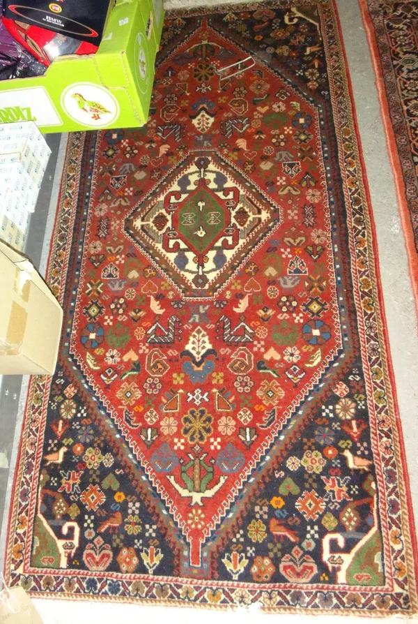 A South Persian rug, the madder field with a diamond medallion, dark indigo spandrels, all with minor motifs, a minor border, 146 x 70cm, together wit