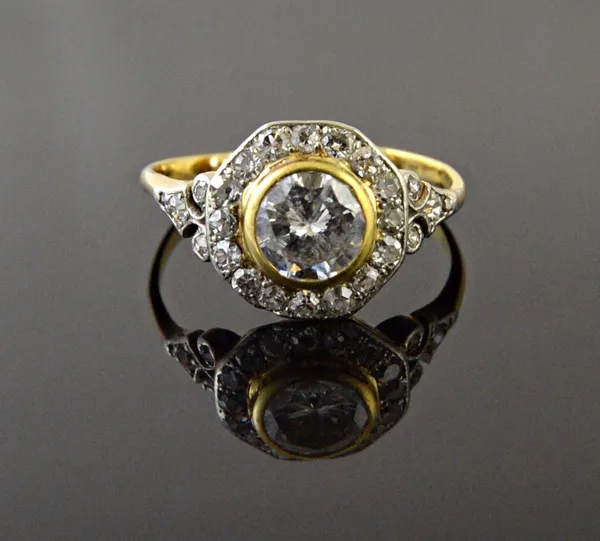 A gold and diamond set cluster ring, collet set with the principal circular cut diamond at the centre, within a surround of cushion shaped and circula