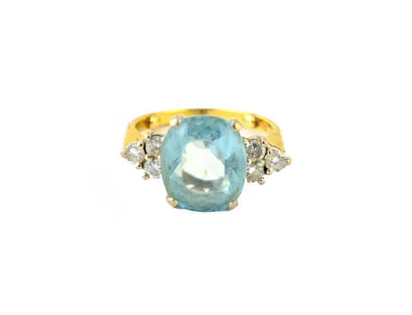 An 18ct gold, aquamarine and diamond set ring, claw set with the oval cut aquamarine at the centre, between circular cut diamond set three stone shoul