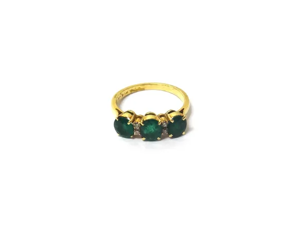 A gold, emerald and diamond set ring, claw set with three oval cut emeralds and with two pairs of small circular cut diamonds, mounted at intervals, d