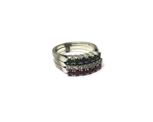A diamond, emerald and ruby set ring, in a triple band design, the central band mounted with a row of nine circular cut diamonds, one side band mounte