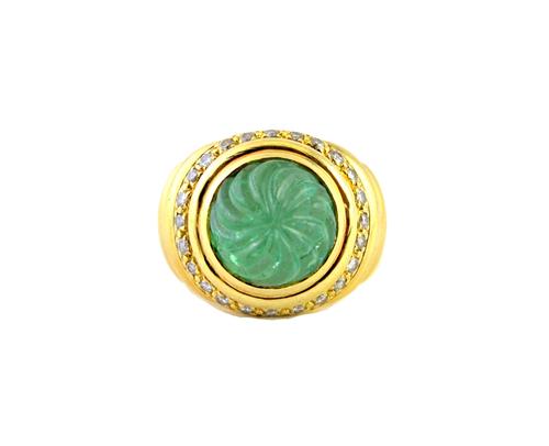 A gold, carved emerald and diamond set ring, detailed Tambetti 18 K, the circular emerald carved in a spiral design, within a border of circular cut d
