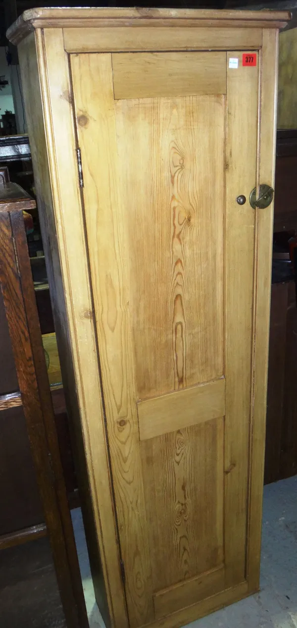 A pine corner cupboard with panelled door.
