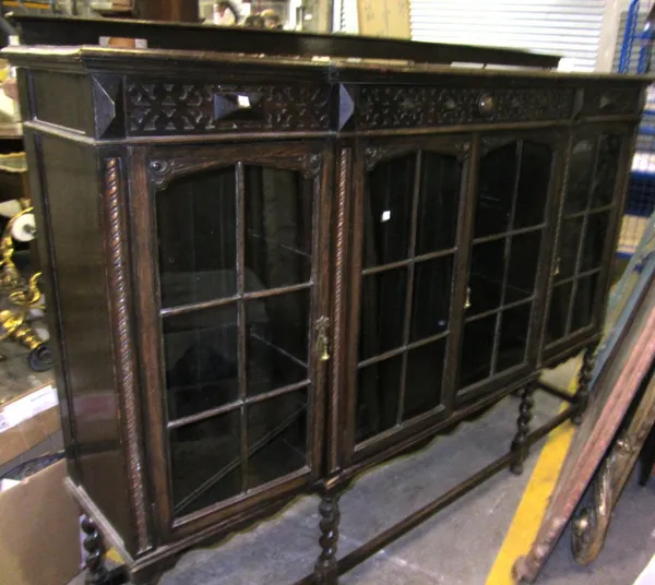 A long 20th century oak bookcase with glazed doors and carved decoration.