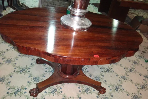 A William IV rosewood centre table, the shaped oval top on tapering octagonal column, on quatrefoil platform and lions paw feet, 130cm wide x 101cm de