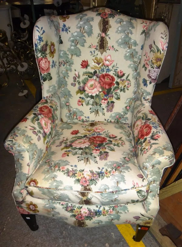An Edwardian mahogany framed wingback armchair, with floral upholstery.