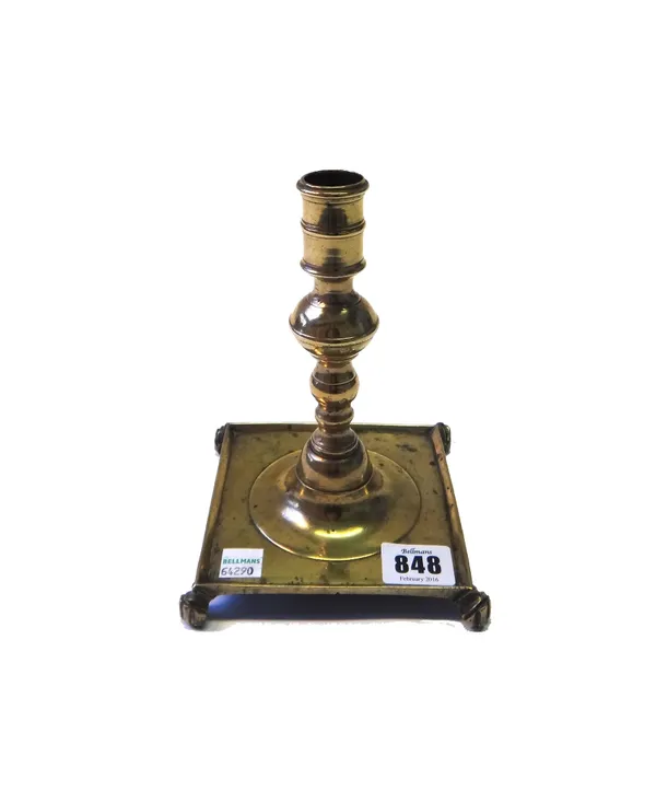 A Spanish brass candlestick, 18th century, with turned and knopped stem on a wide square base and lions paw feet, 17cm high.
