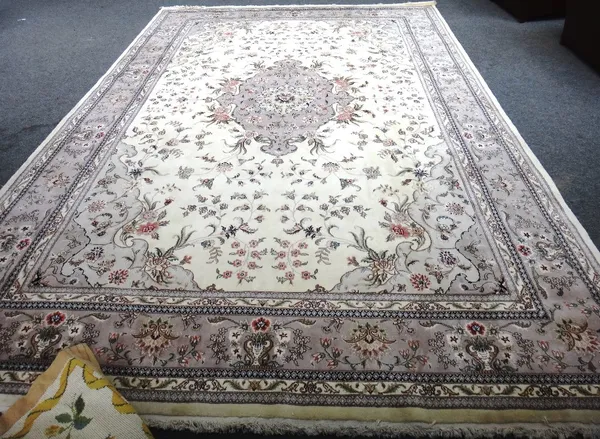 A Chinese carpet, the ivory field with grey medallion, cut to centre, 432cm x 300cm