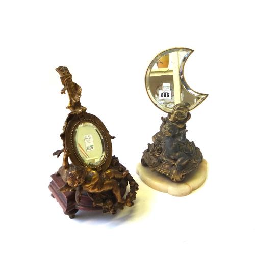 An early 20th century French gilt spelter figural table mirror modelled and cast as a cherub beneath a crescent moon and another similarly cast mirror