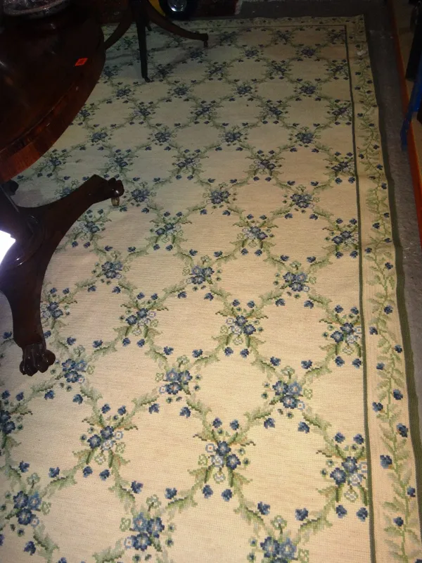 A needlework carpet, the ivory field with a blue floral trellis, 336cm x 297cm.